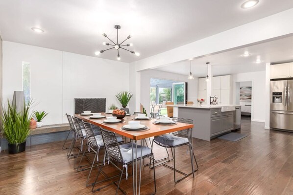 A modern kitchen with a central island, wooden dining table, and chairs. - Ochenta Modern Retreat Htd Pool Spa Putt Grn Gym (Scottsdale)