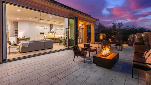Ein modernes Haus mit offener Wohnbereitschaft, einer Küche und einer Terrasse mit Gartenmöbeln und Feuerstelle.