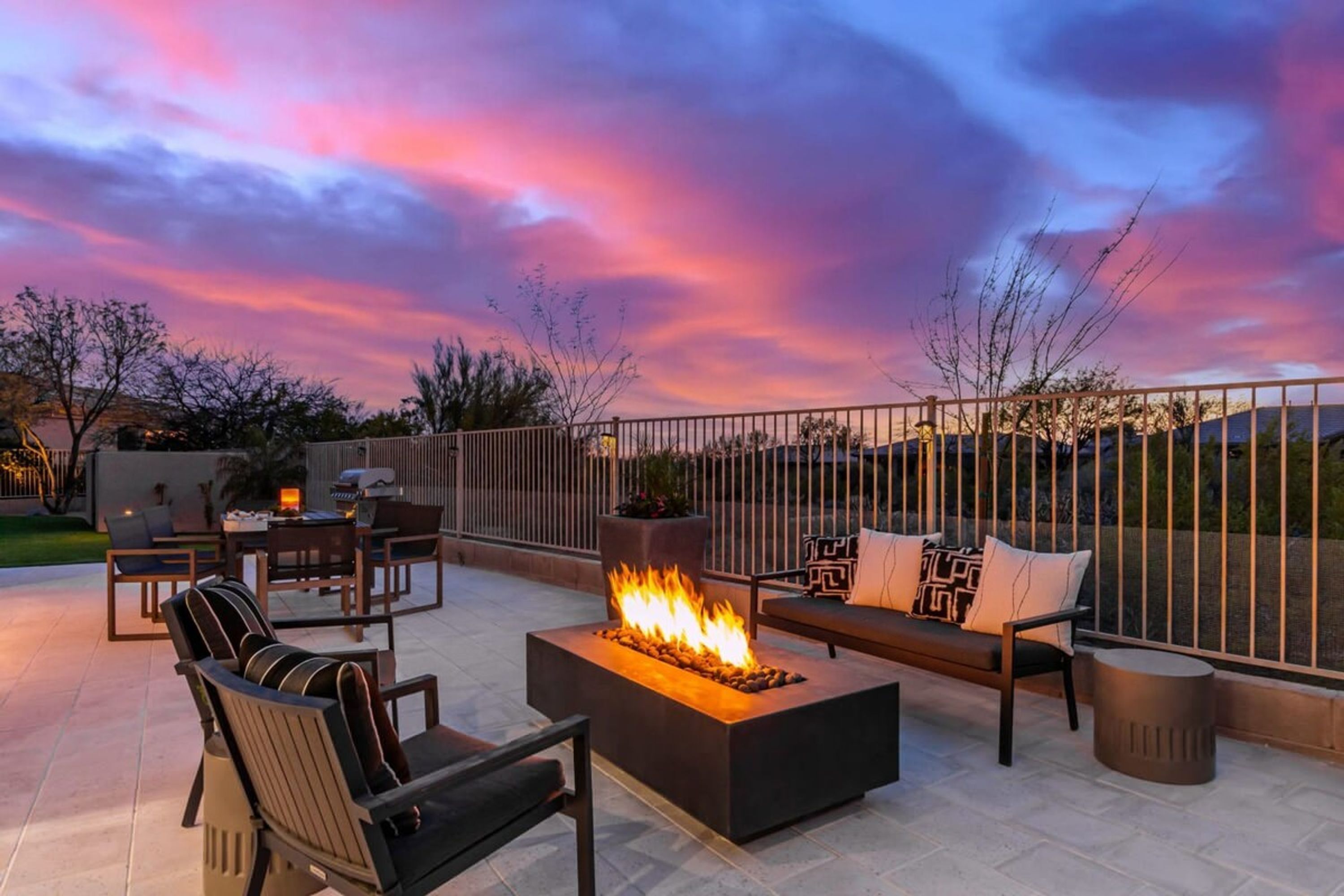An outdoor patio with a fire feature, seating, and a view of the sky.