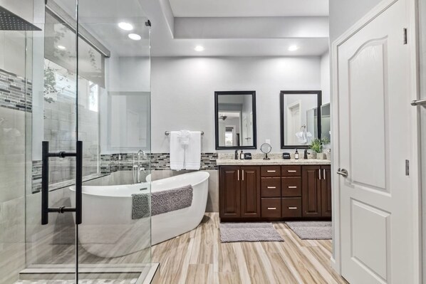A modern bathroom with a glass-enclosed shower, a freestanding bathtub, and a vanity with dark wooden cabinets. - Sunset View Retreat Pool Spa Amazing Views (Scottsdale)