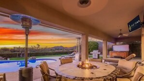 A patio with a round table, chairs, a fire pit, and a view of a swimming pool and mountains. - Sunset View Retreat Pool Spa Amazing Views (Scottsdale)