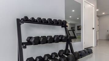 A gym with a rack of dumbbells and a large mirror on the wall.
