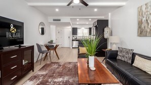A modern living room with a flat-screen TV, a sofa, a coffee table, and a dining area with a table and chairs. - Walk 2 Old Town - Pool View Fashion Square (Scottsdale)