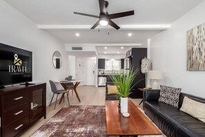 A modern living room with a flat-screen TV, a sofa, a coffee table, and a dining area with a table and chairs. - Walk 2 Old Town - Pool View Fashion Square (Scottsdale)