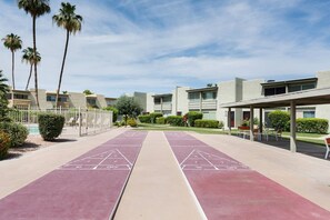 Un patio con canchas de juego de hojalata, palmeras y edificios modernos.