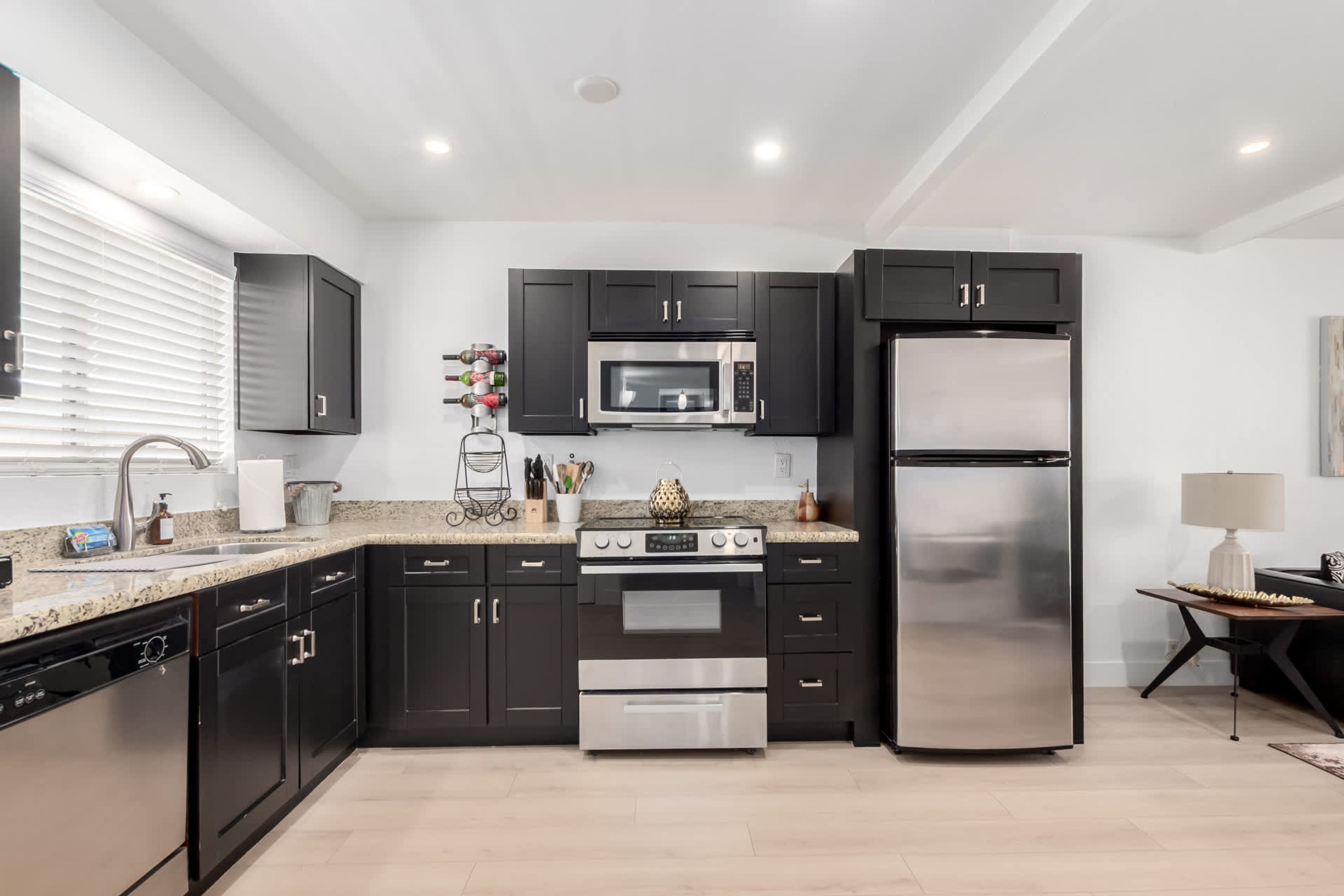 A modern kitchen with black cabinets, stainless steel appliances, and a granite countertop.