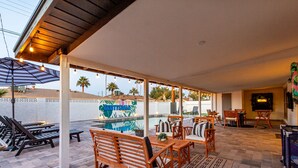 A covered outdoor area with a pool, lounge chairs, wooden furniture, and string lights. - Palmhouse Pool BBQ 5 Mins to Old Town (Scottsdale)
