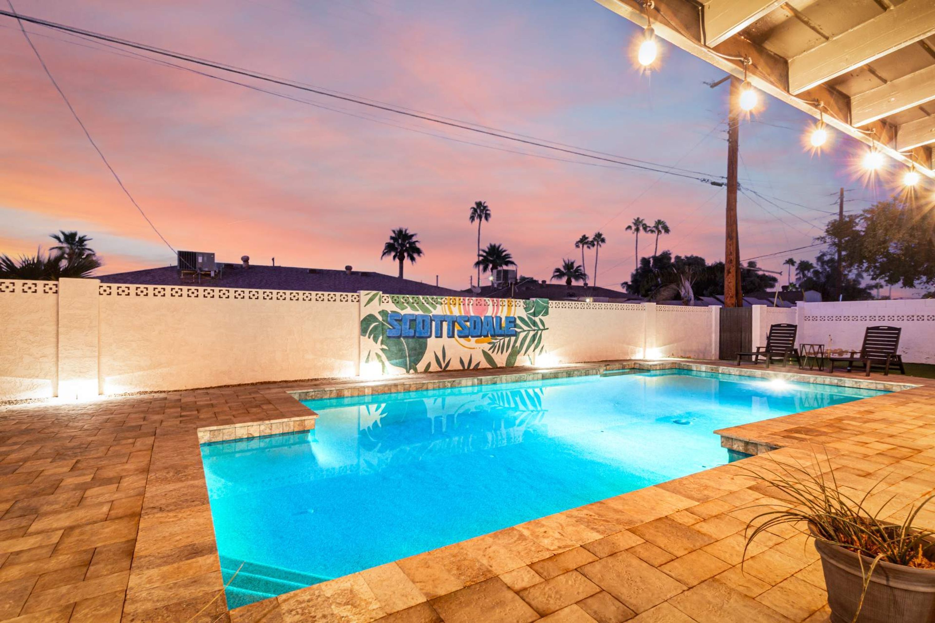 A swimming pool with a sign reading "SCOTTSDALE" and palm trees in the background.