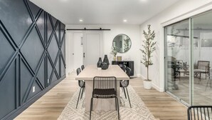 A modern dining area with a long table, black chairs, and a potted plant. - Palmhouse Pool BBQ 5 Mins to Old Town (Scottsdale)