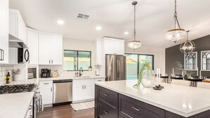 A modern kitchen with white cabinets, stainless steel appliances, and a large island. - Broadway Palms Private Pool Chef Kitchen Office (Tempe)