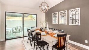 A dining area with a large table set for six, surrounded by black chairs. There is a chandelier above the table, and the walls are painted in a neutral tone. - Broadway Palms Private Pool Chef Kitchen Office (Tempe)