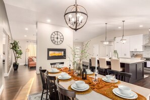 A modern dining area with a central island, white walls, and a large clock. - Broadway Palms Private Pool Chef Kitchen Office (Tempe)