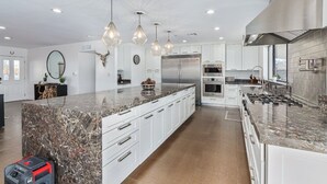 A modern kitchen with white cabinetry, granite countertops, stainless steel appliances, and pendant lighting. - Scottsdale s Largest Hot Tub Davenport Ranch Estate (Scottsdale)