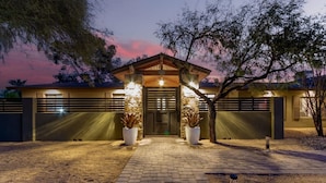 A building with a stone facade, a central entrance with a wooden canopy, and two large potted plants on either side. - Scottsdale s Largest Hot Tub Davenport Ranch Estate (Scottsdale)