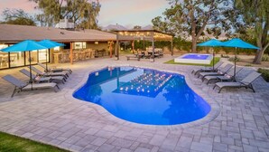 A swimming pool with lounge chairs and umbrellas, surrounded by a patio area with a covered seating space. - Scottsdale s Largest Hot Tub Davenport Ranch Estate (Scottsdale)