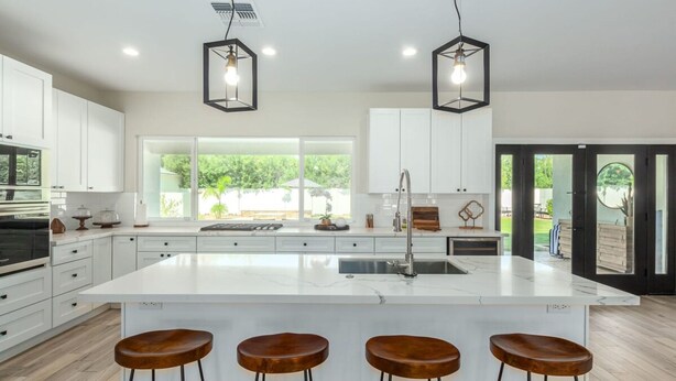 A modern kitchen with white cabinets, a large island with stools, and pendant lighting. - Modern Arcadia Estate Htd Pool Bikes Chef Kitchen (Phoenix)
