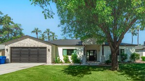 A single-story house with a garage, a front porch, and a large tree in front. - Modern Arcadia Estate Htd Pool Bikes Chef Kitchen (Phoenix)