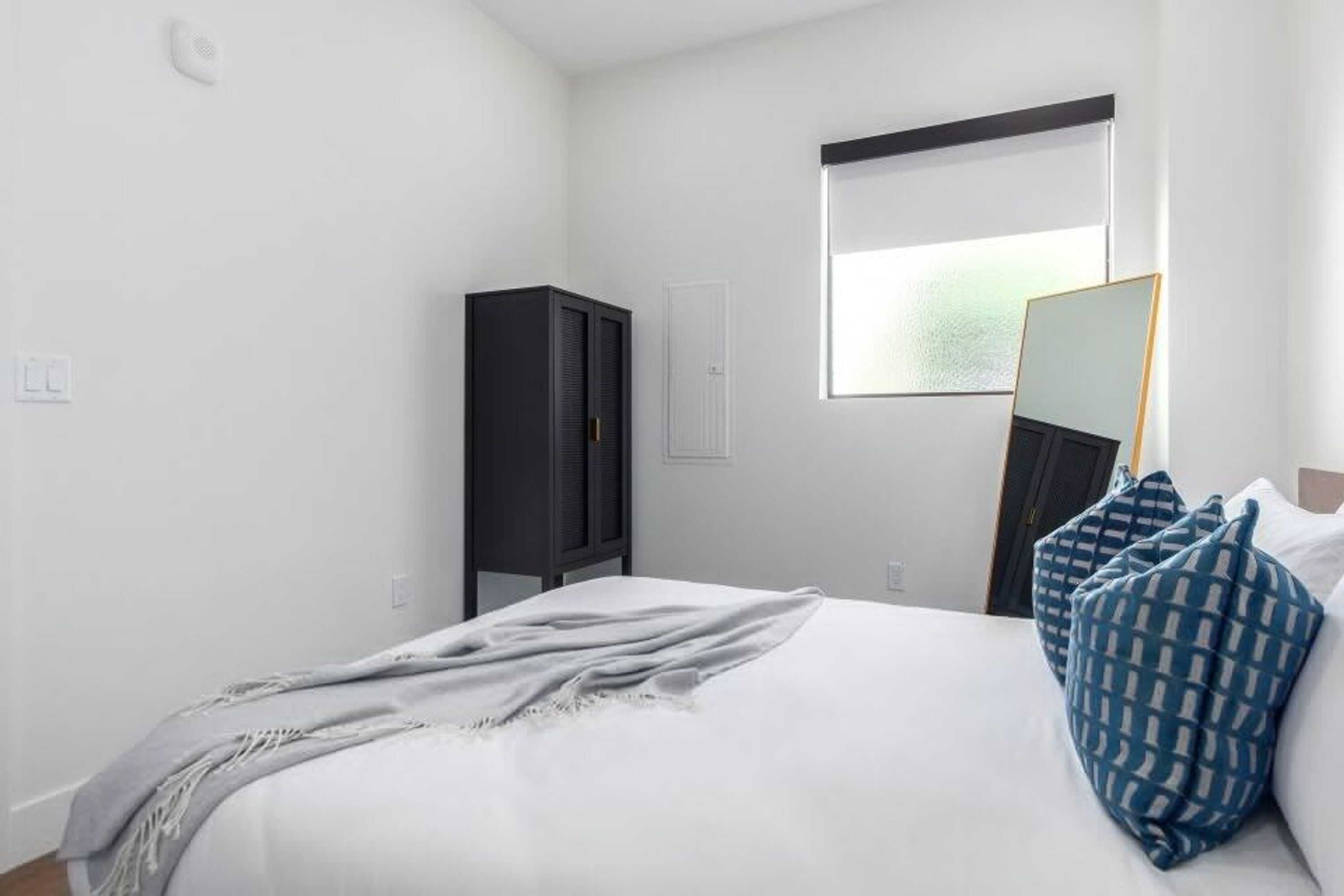 A bedroom with a bed, a wardrobe, a window, and a mirror.