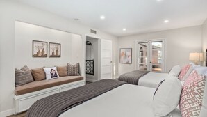 Habitación de hotel moderna con una cama grande, un sofá cama y un pequeño rincón de descanso. Hay dos cuadros en la pared, una puerta que da a un balcón y una ventana con vistas al exterior.