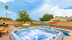 Un jacuzzi en un patio trasero con terraza, un mural y una piscina.