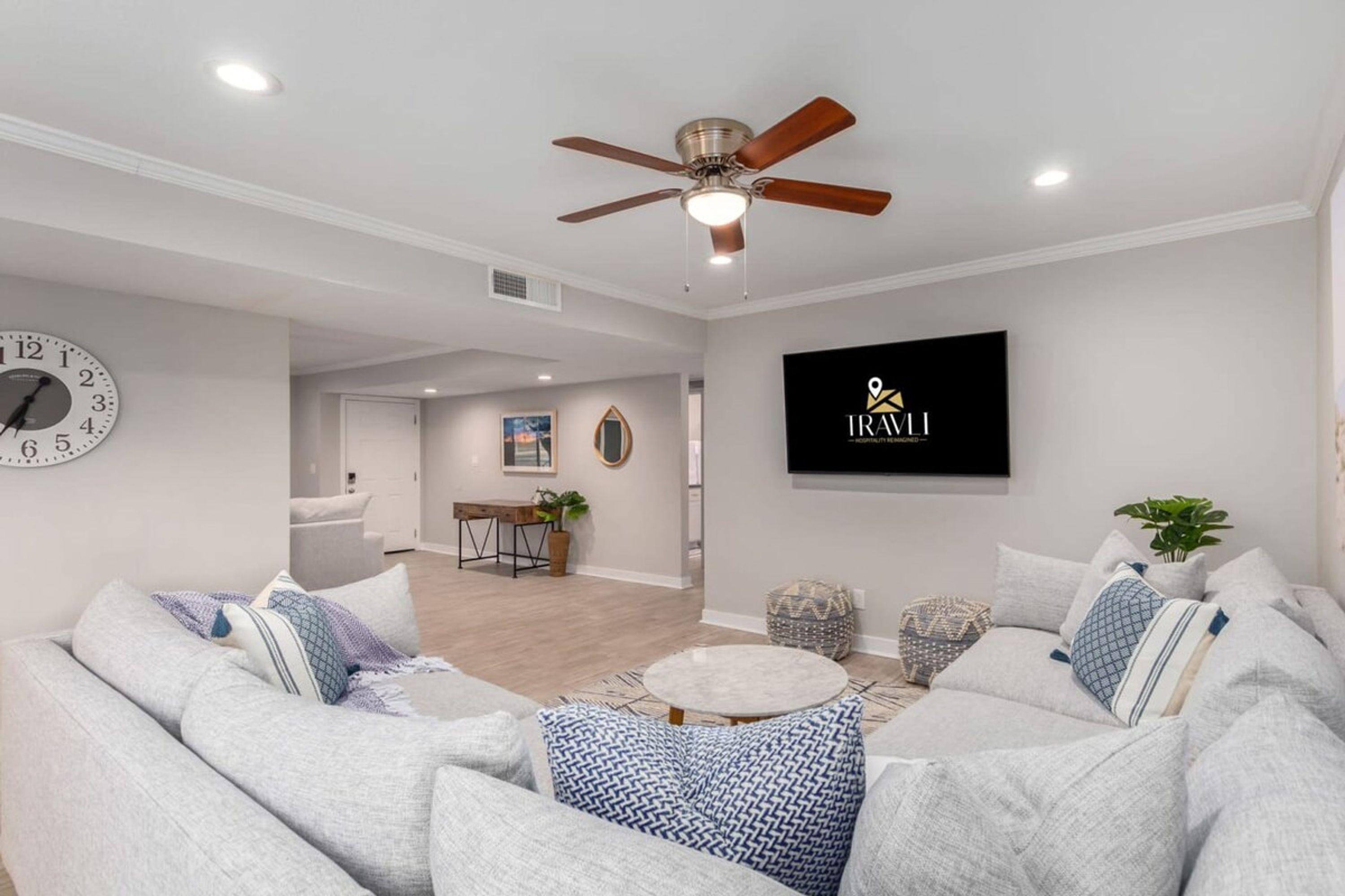 A modern living room with a ceiling fan, a round coffee table, and a sofa with patterned cushions.