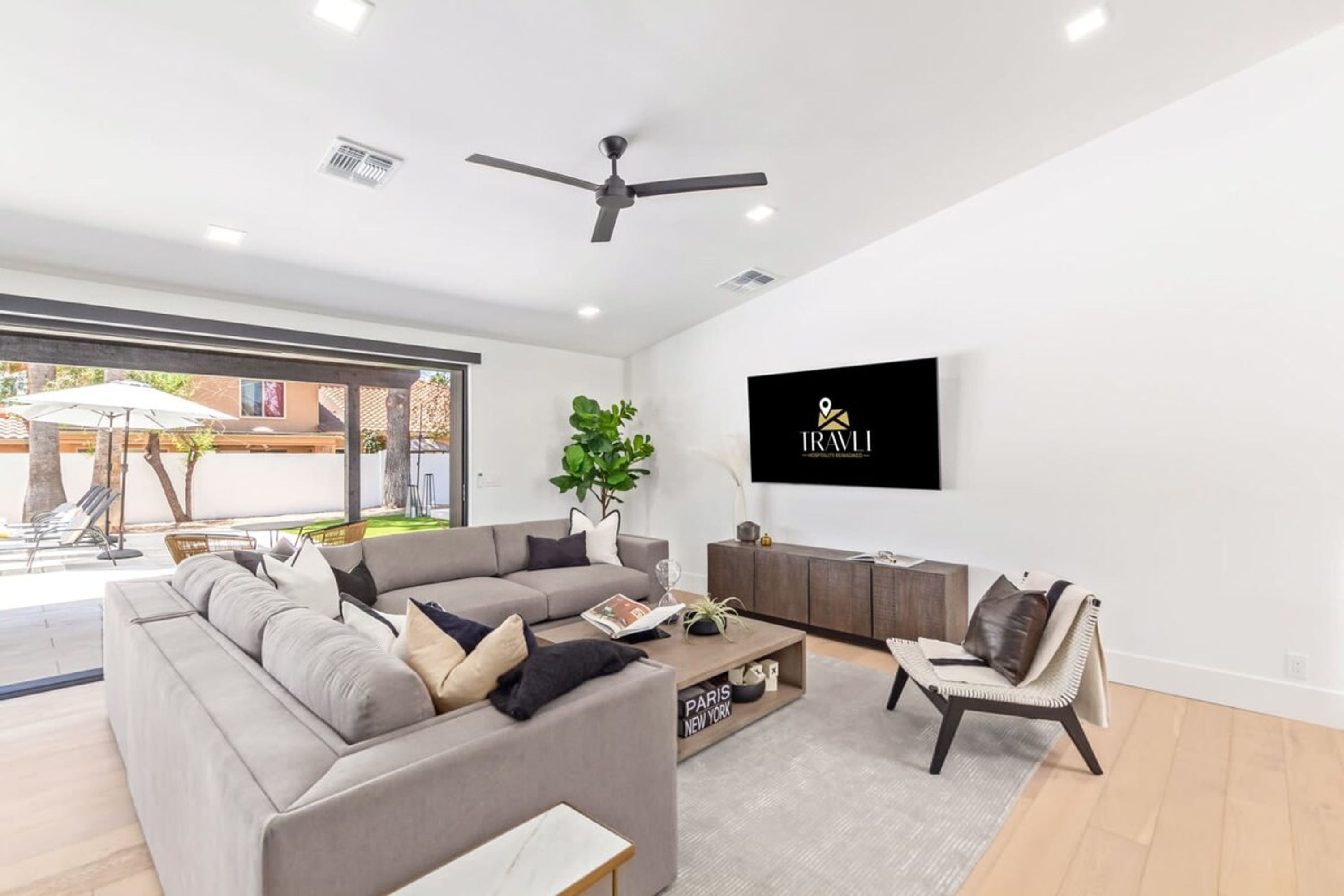 A modern living room with a grey sectional sofa, a coffee table, and a TV mounted on the wall.