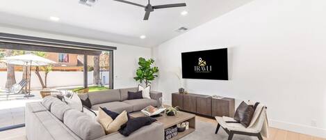 A modern living room with a grey sectional sofa, a coffee table, and a TV mounted on the wall.
