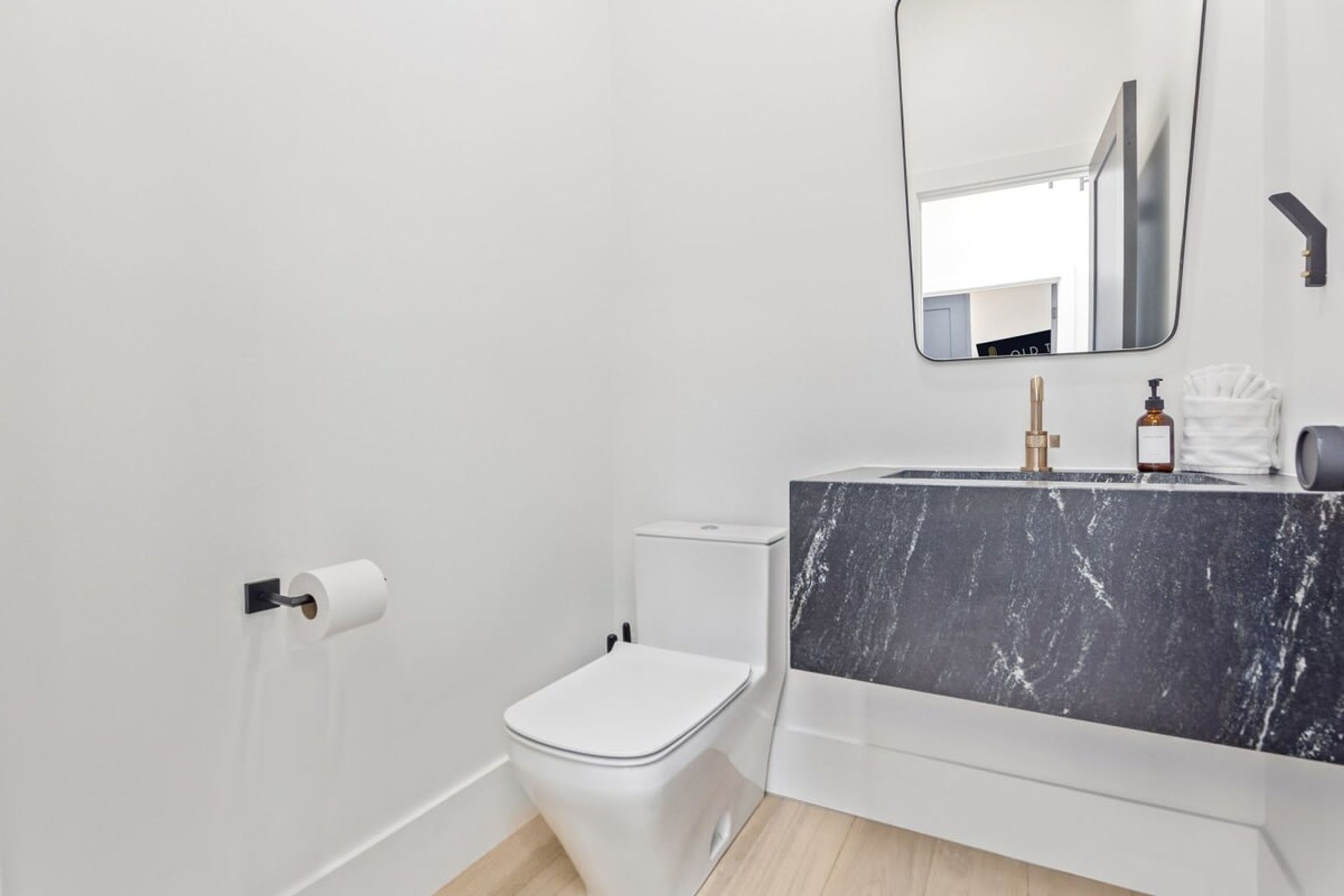 Ein modernes Badezimmer mit Toilette in Weiß, einem мраморбетонном Waschbecken und einem Spiegel darüber.