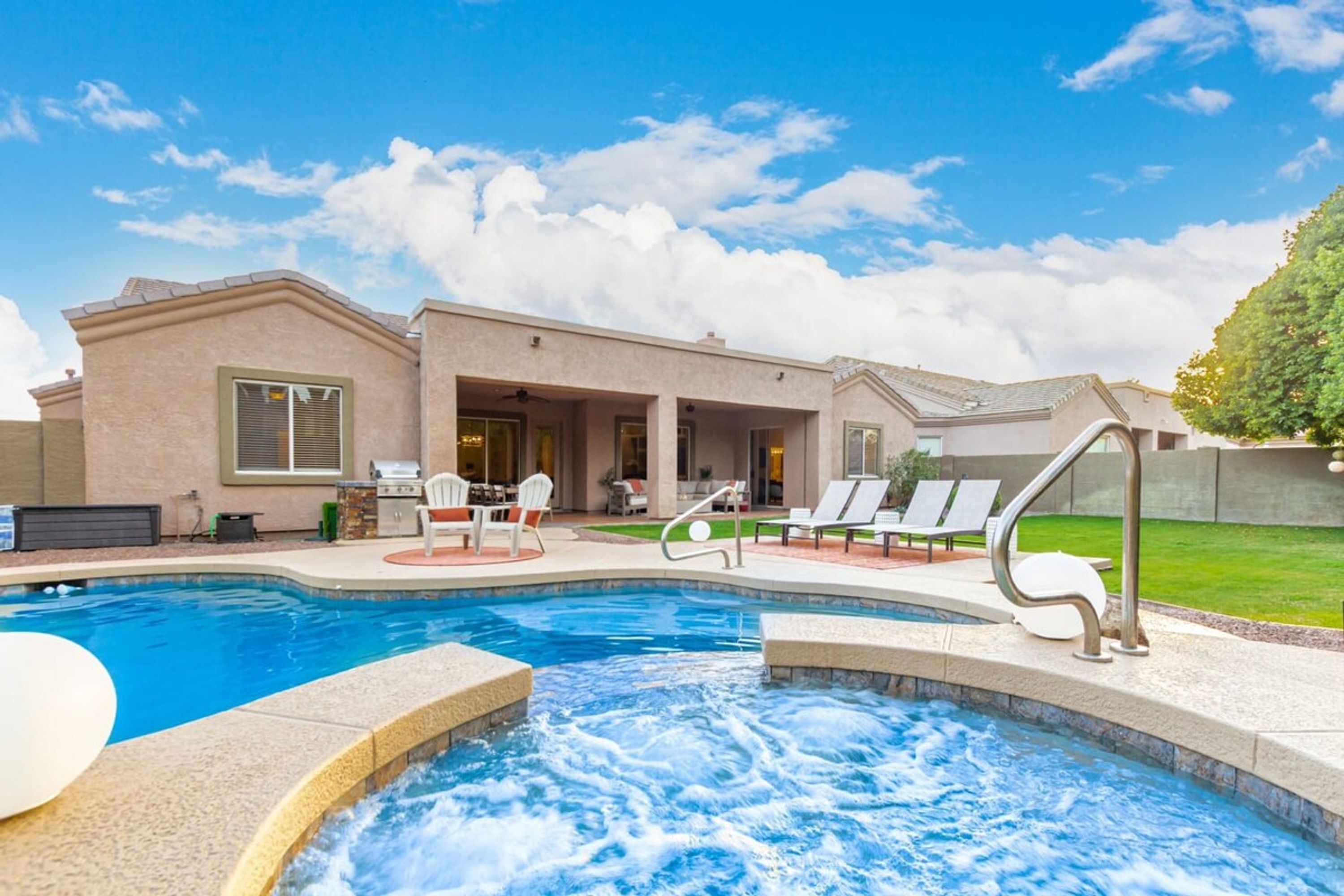 Una casa moderna con piscina, mobiliario de exterior y bañera de hidromasaje.