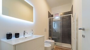 Une salle de bain moderne avec un meuble-lavabo blanc, une douche en verre et des toilettes.
