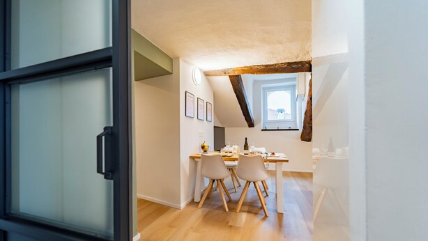 A modern kitchen with wooden flooring, a dining area with two chairs, and a window with a view. - La Dimora di Barbaroux (Cuneo)