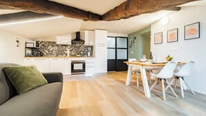 A modern kitchen with white cabinets, a patterned backsplash, and a dining area with a wooden table and white chairs. - La Dimora di Barbaroux (Cuneo)