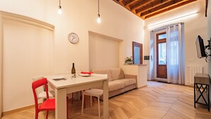 A dining area with a table set for two, a red chair, and a sofa. - La Dimora di Filippo (Cuneo)