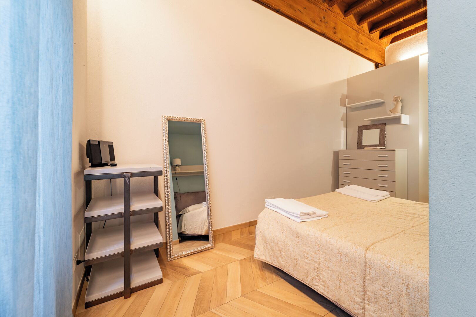 Ein Schlafzimmer mit einem Bett, einem Spiegel, einer Kommode und einem Regal.