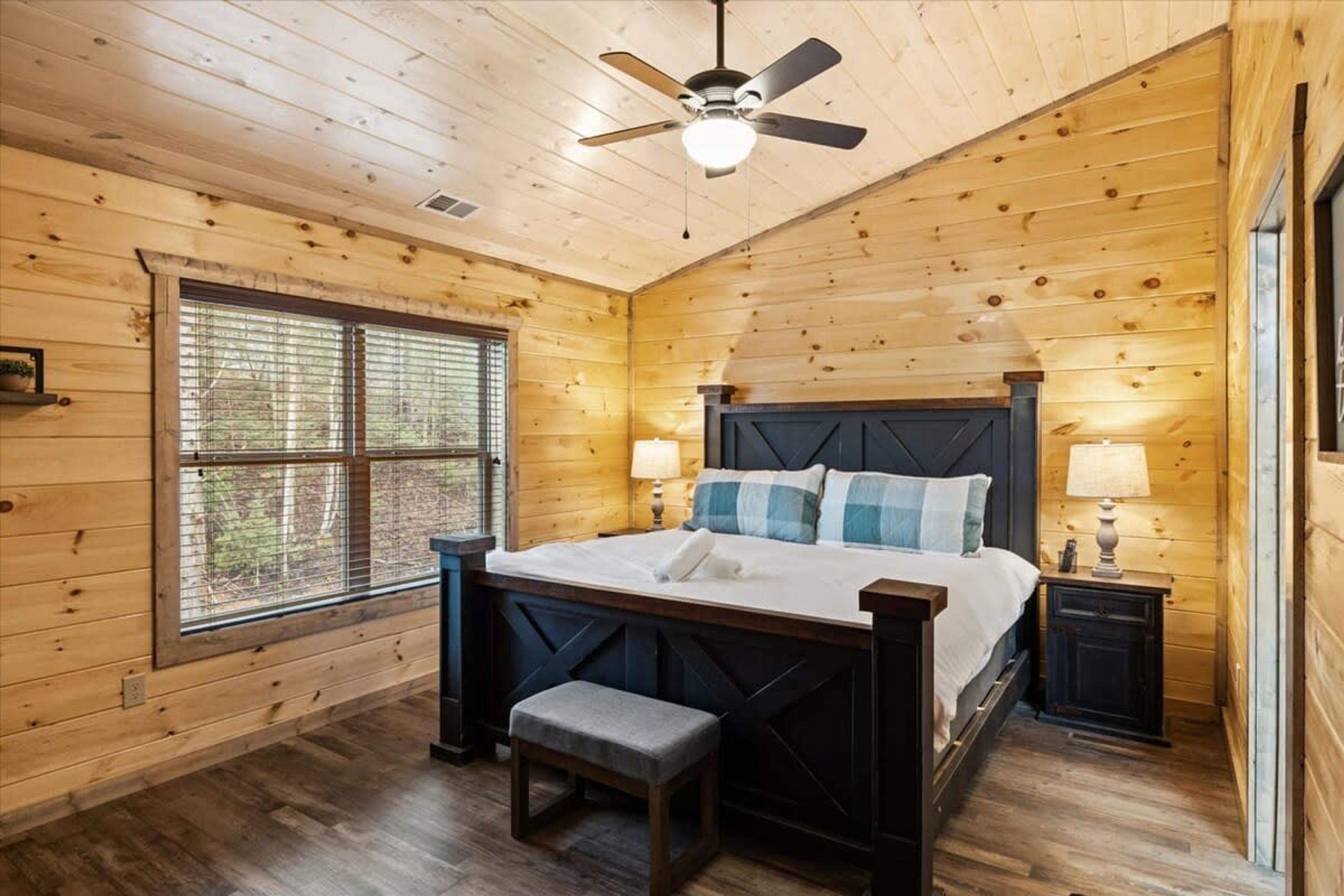 Une chambre dans une cabane en bois, avec un lit, un banc et deux tables de chevet.