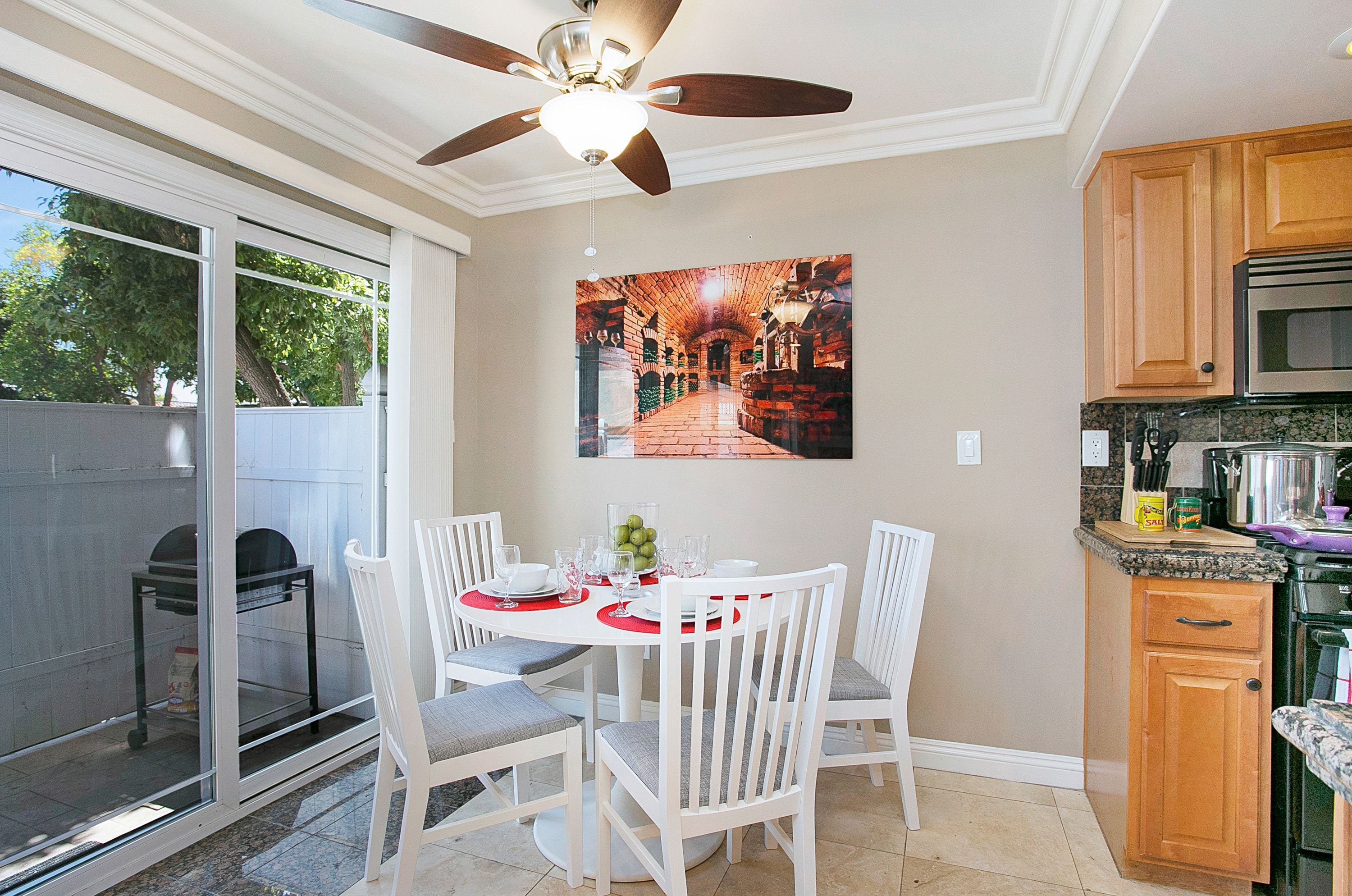 A dining area with a round table, white chairs, and a ceiling fan.