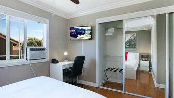 Une chambre à coucher comprenant un lit, un bureau, une chaise, une télévision et un placard à portes coulissantes.