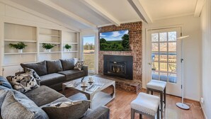 A living room with a fireplace, a sofa, a coffee table, and shelves with plants.
