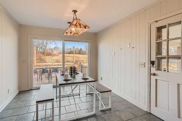 A dining area with a table and benches, a hanging light fixture, and a door with a window. - 1 Country House Game Room BBQ Near Nashville TA (Franklin)