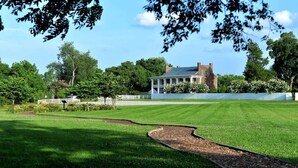 A large, well-maintained lawn with a curved pathway leading to a white building with a dark roof.