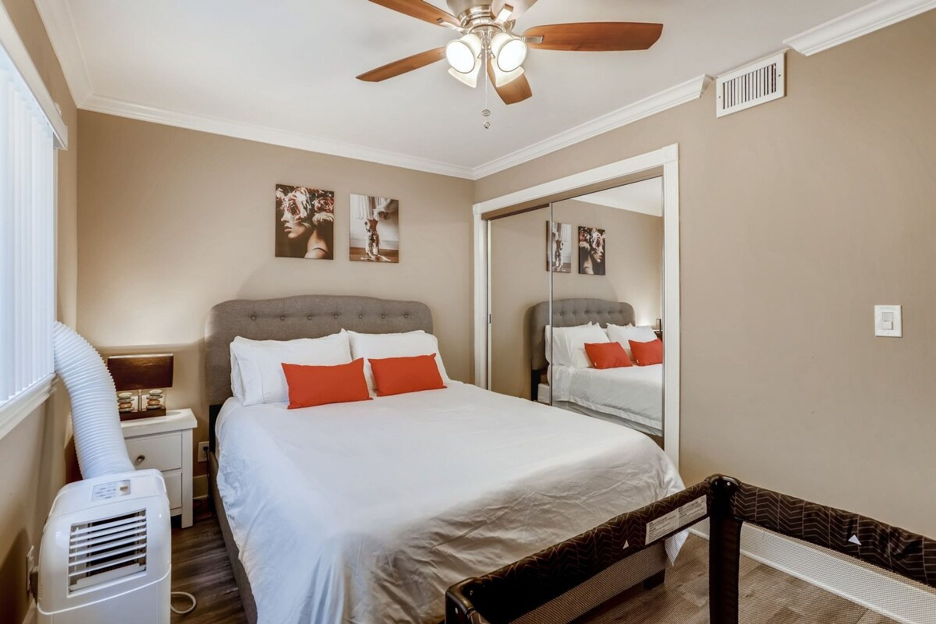 Un dormitorio con una cama, ventilador de techo, calefactor y espejo.