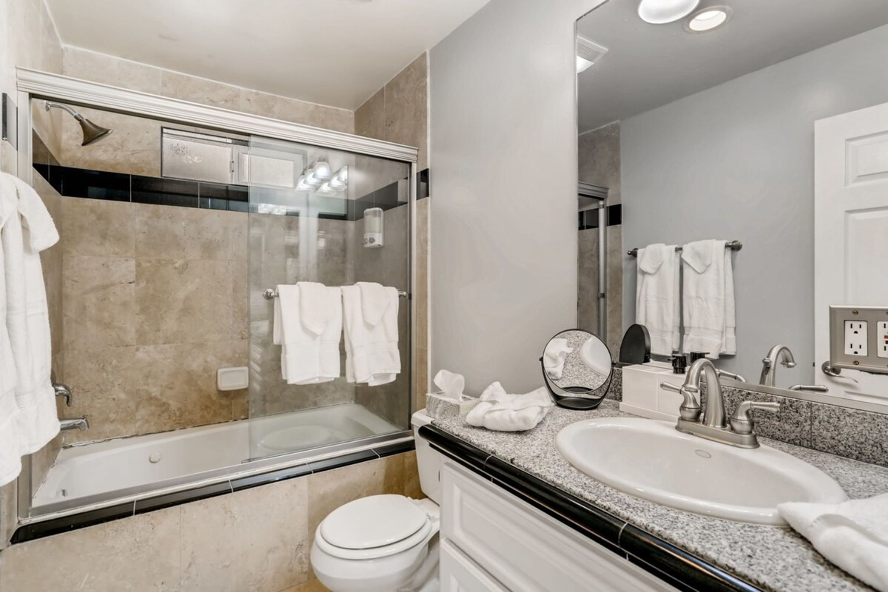 A modern bathroom with a glass-enclosed shower, a standalone sink, and a toilet.