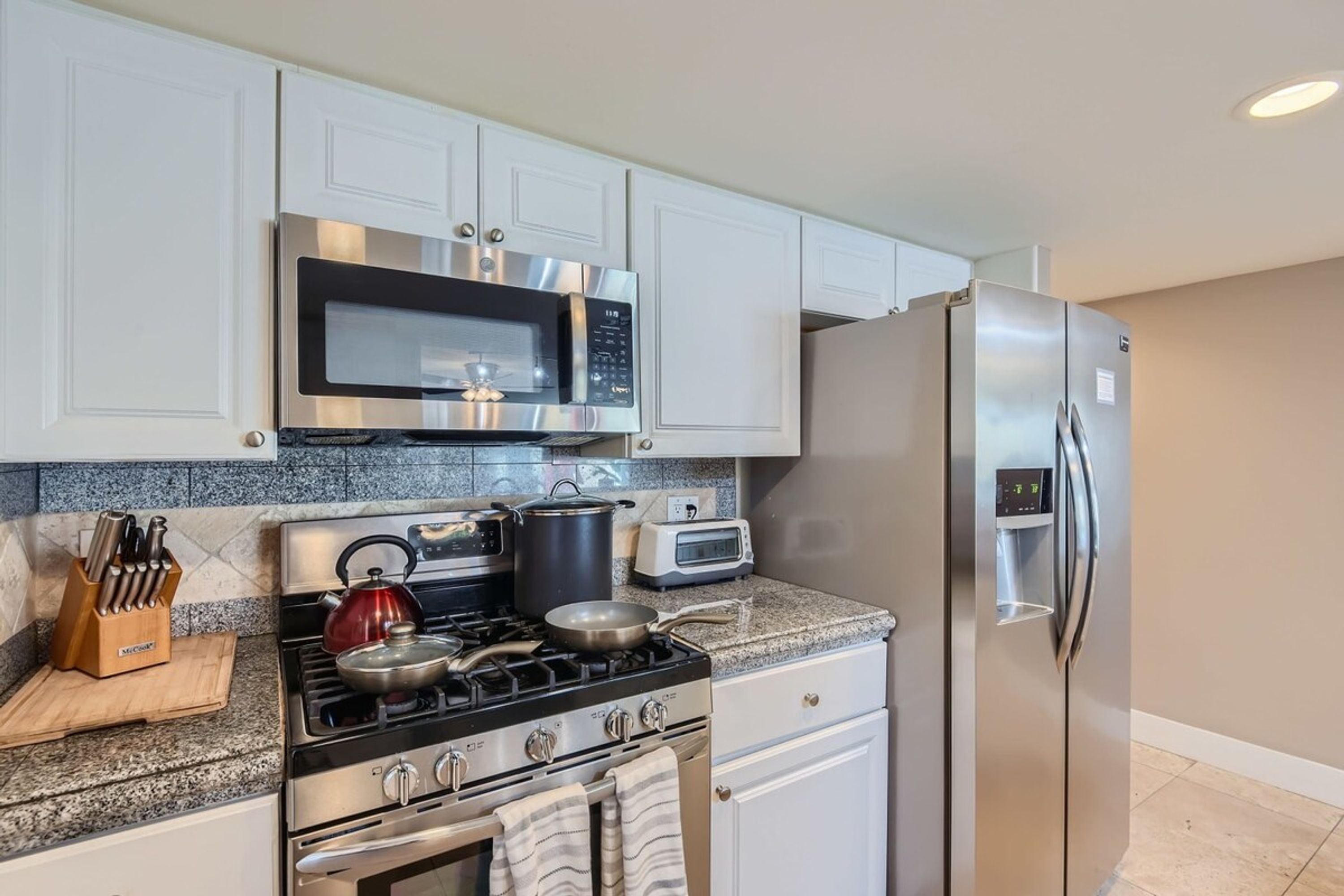 A modern kitchen with stainless steel appliances, a gas stove, a microwave, a refrigerator, and a toaster.