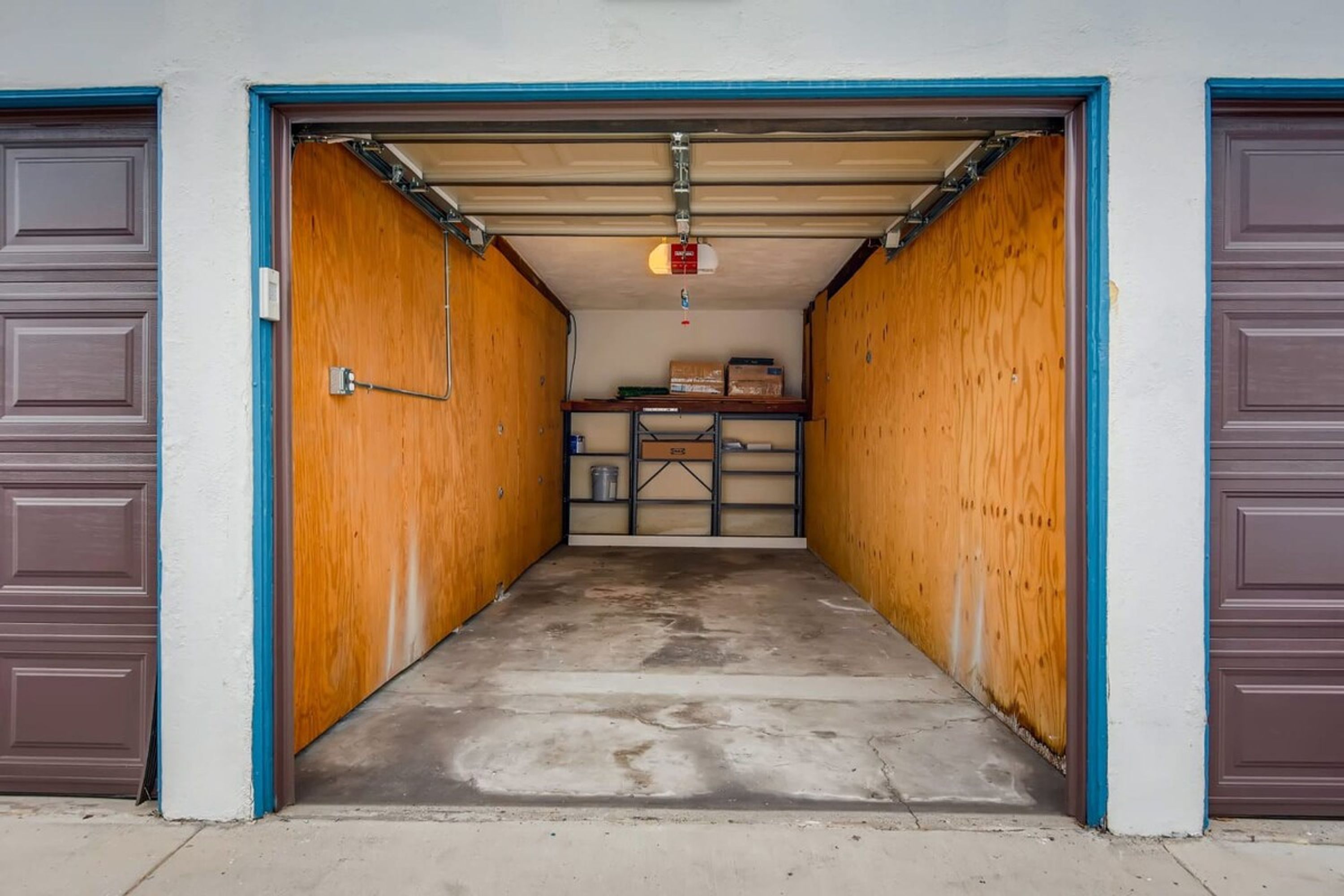 A garage with wooden walls and a concrete floor, leading to a garage door.