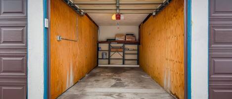 A garage with wooden walls and a concrete floor, leading to a garage door.