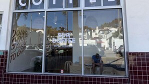 A coffee shop with a large window displaying the word "COFFEE" and a sign that says "SUR COFFEE".