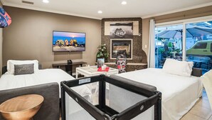 Habitación de hotel con dos camas, televisión, chimenea y vistas al exterior.
