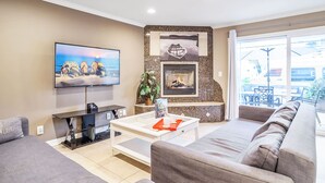 Una sala de estar con televisor, chimenea, sofá y mesa de centro.