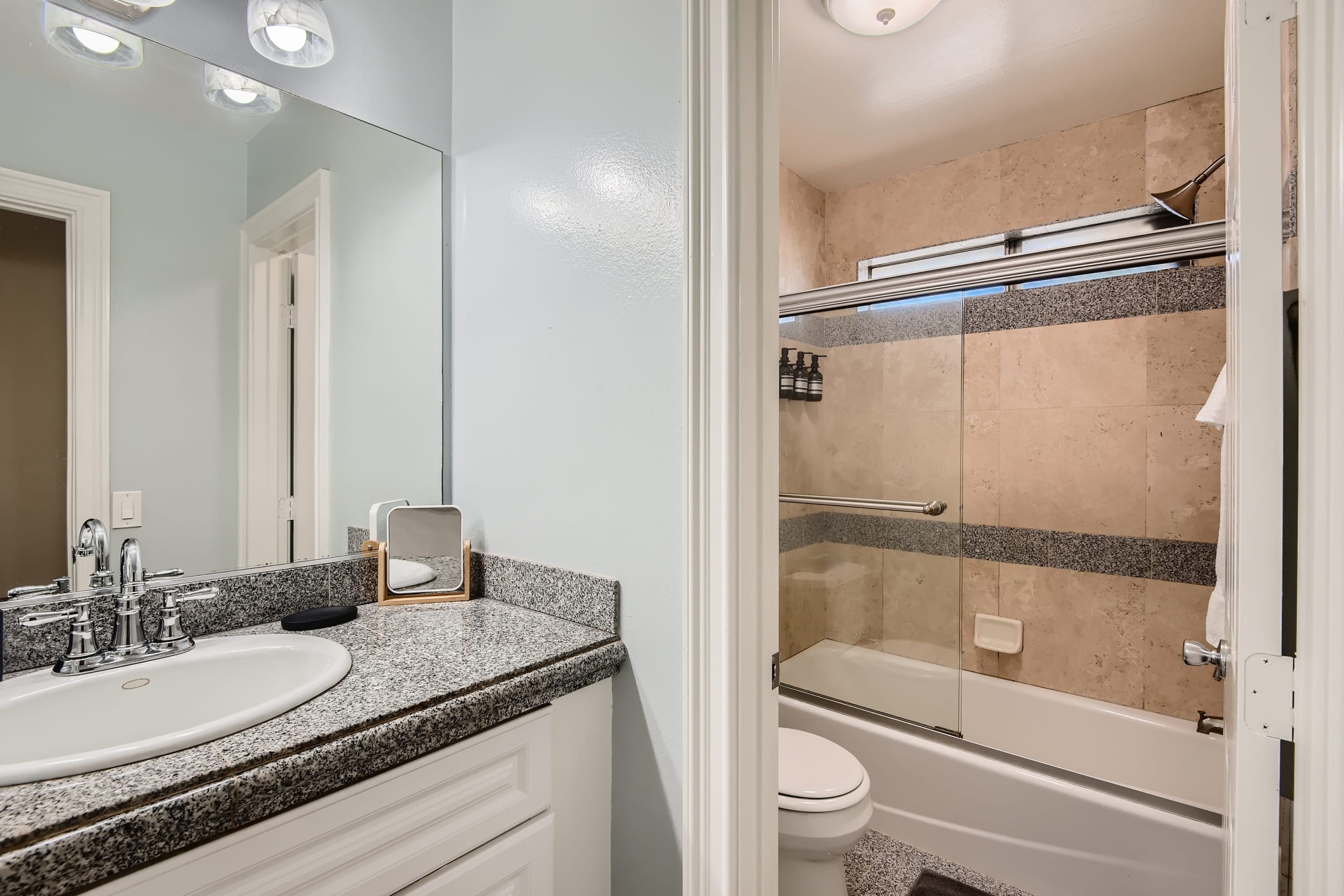A bathroom with a sink, mirror, and shower area.