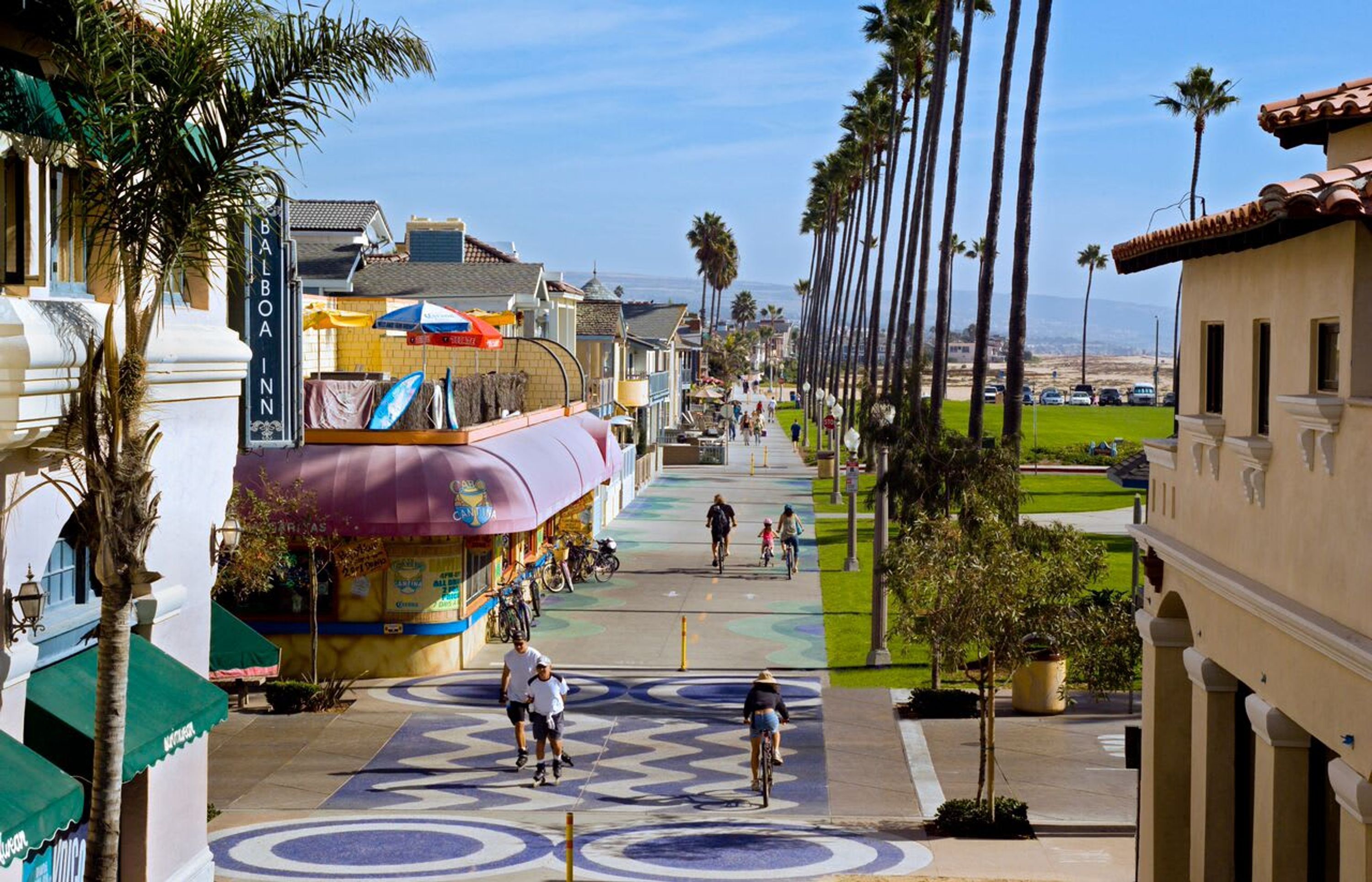 Una calle con el Balboa Inn, palmeras y un paseo peatonal.